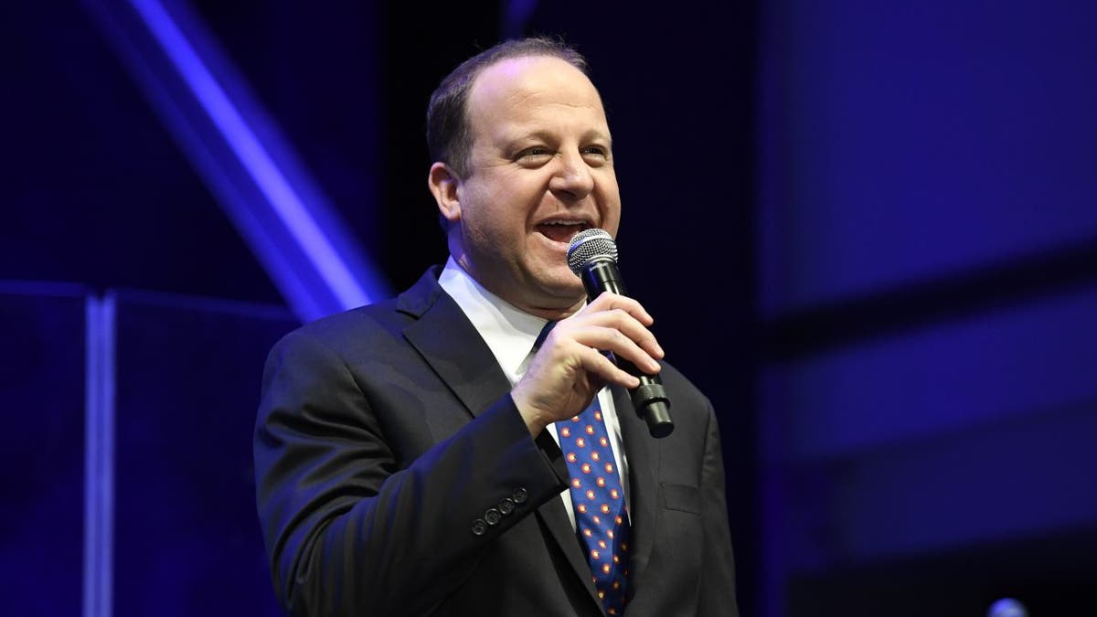 Gov. Jared Polis holding microphone