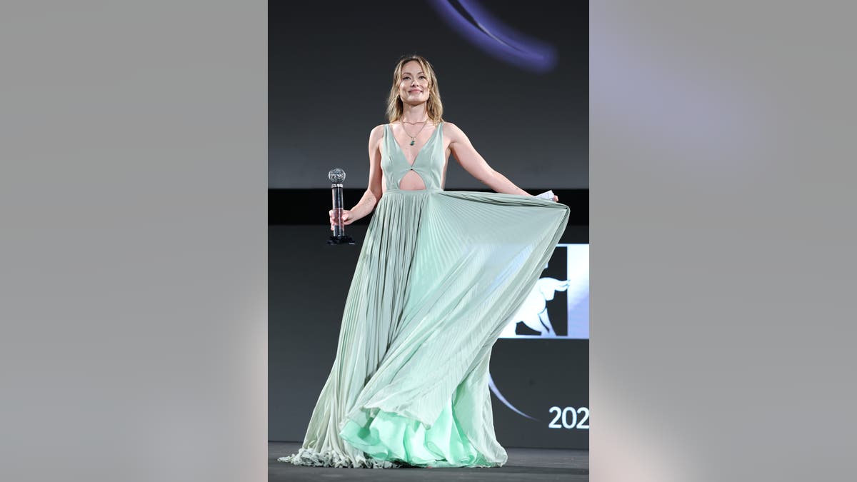 Olivia Wilde smiles and holds her award while on stage at the Taormina Film Festival.
